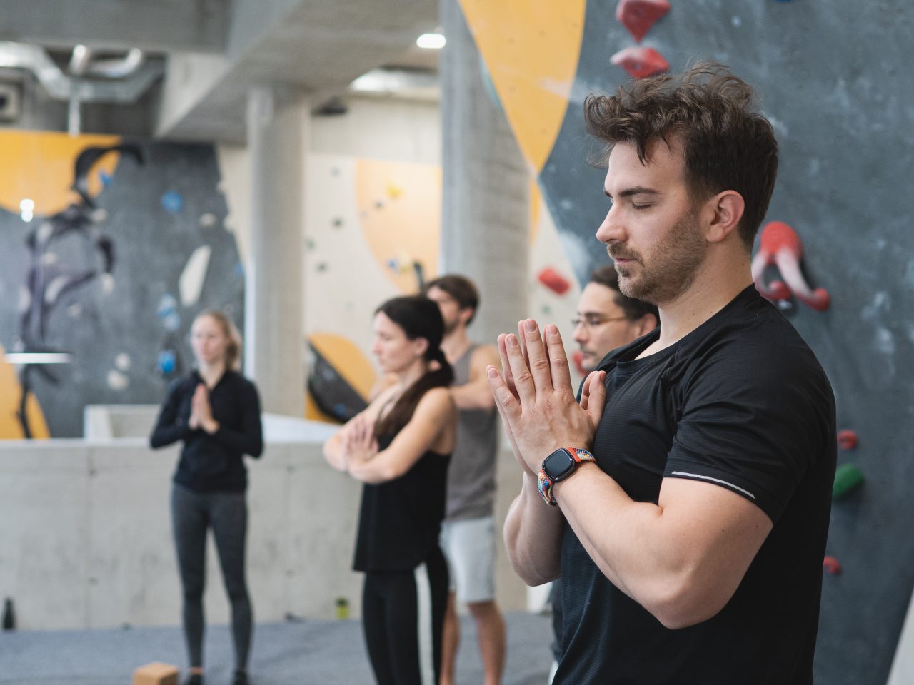 Gruppe macht Yoga vor Boulderwand