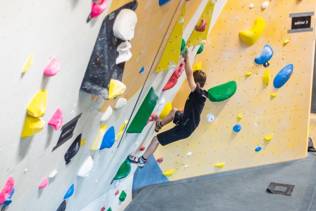 Kind klettert bei Boulderbewerb