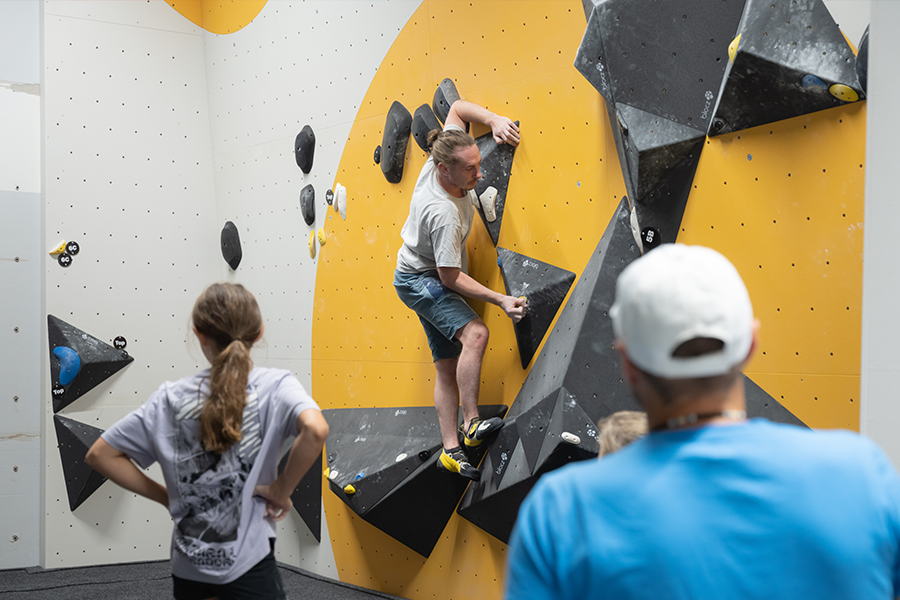 Kletternder an der Wand und zwei Zusehende