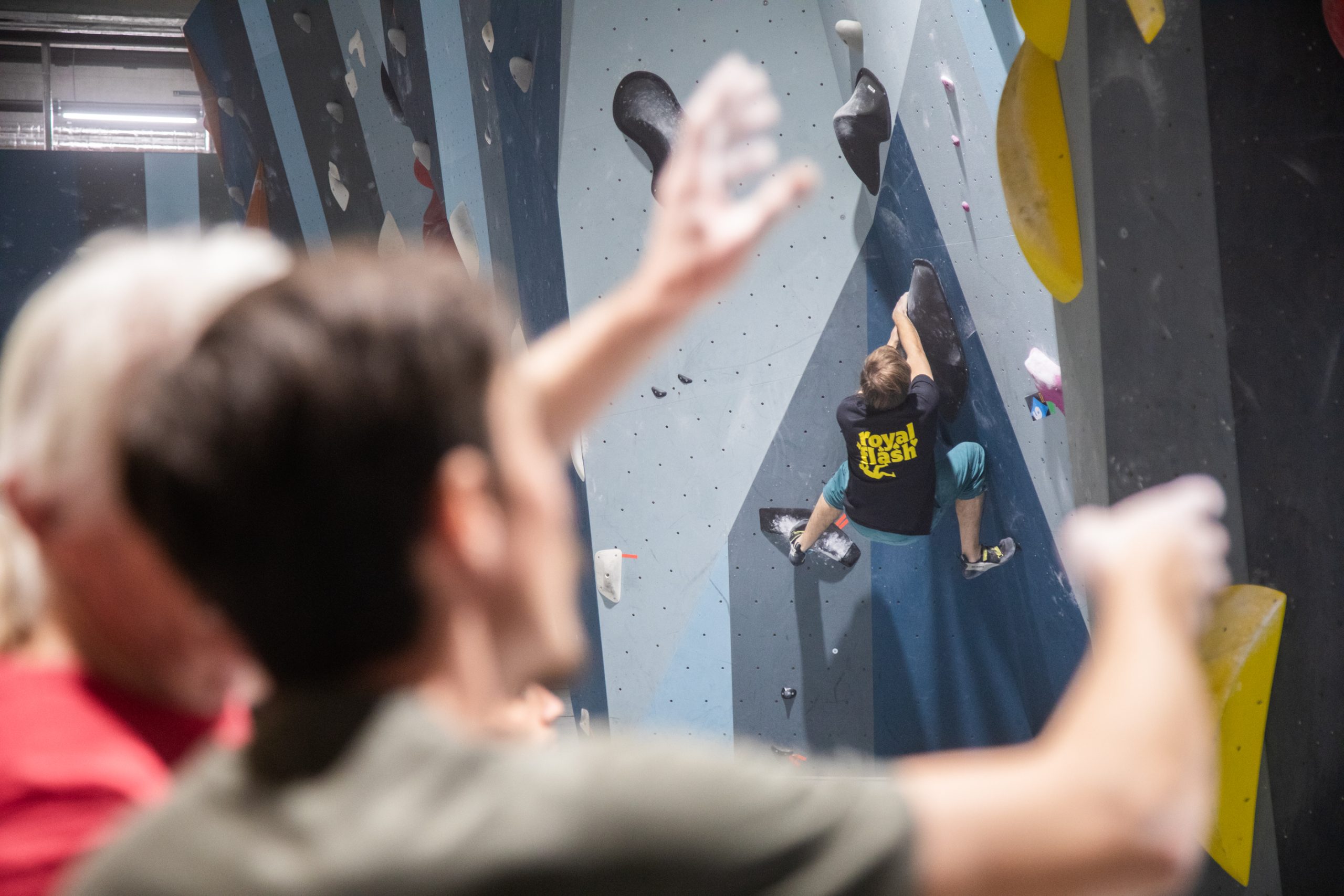 Kletterer bei Boulderbewerb in der boulderbar Linz mit 2 Zusehenden