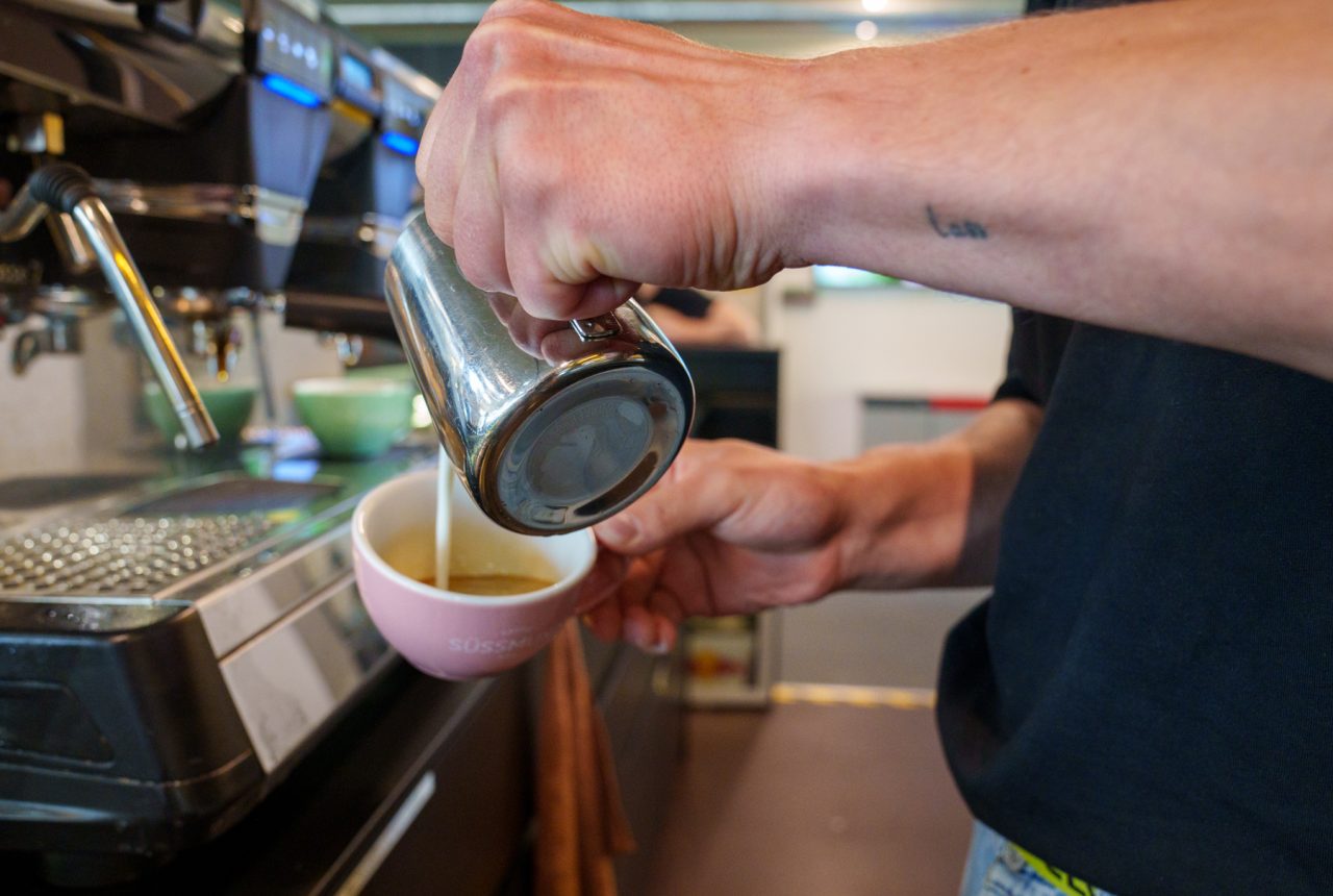 boulderbar Mitarbeiter giesst Milch in Cappuccino