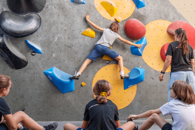 Kind klettert eine Boulderroute